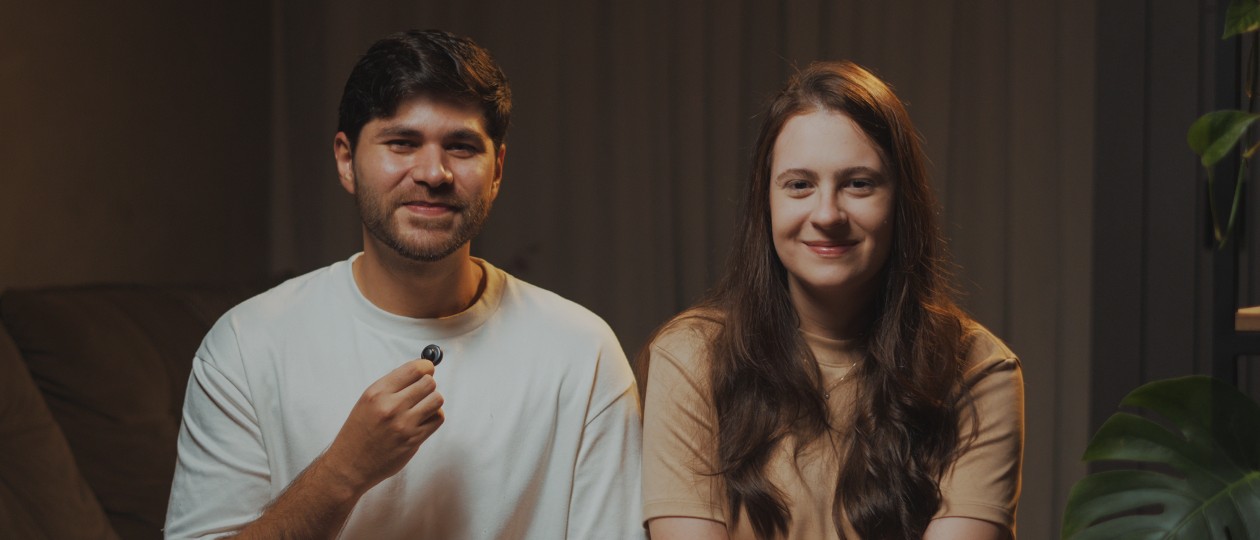 Bianca e Iury, lado a lado no sofá, sorrindo para a câmera.